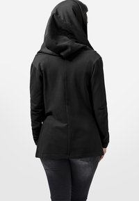 Sweatshirt à capuche noir avec une silhouette structurée, des manches longues et une texture de tissu lisse. Des coutures décoratives descendent à l'arrière.