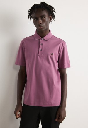 Polo à manches courtes en lavande avec un col à trois boutons, logo brodé sur la poitrine et tissu en coton doux.