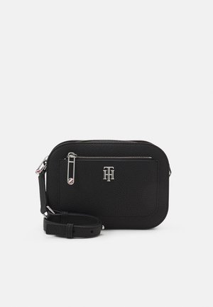 Sort textured læder crossbody taske med sølv lynlås, forlommer, logemblem og justerbar rem på hvid baggrund.