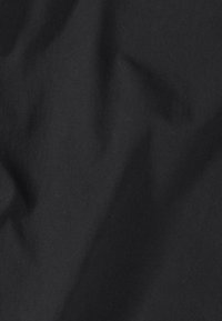 Schwarzer Stoff mit diagonalem Köperbindemuster und dezenten Falten, die weiche Schatten und Textur erzeugen.