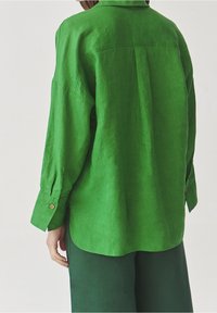 Groene linnen overhemden met kolletje, lange mouwen en knoopmanchetten. Getextureerde stof met een iets losse pasvorm en een gebogen zoom.