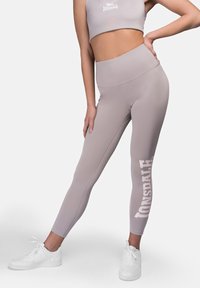 Leggings gris claro de cintura alta, hechos de un material elástico, con un estampado de logotipo blanco en la parte inferior de la pierna, combinados con un top corto a juego.