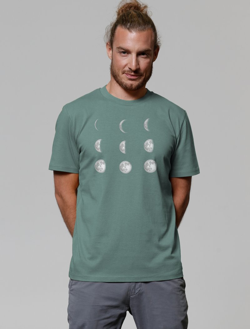 Grünes Baumwoll-T-Shirt mit einem weißen Mondphasen-Grafik. Kurze Ärmel, runder Ausschnitt und lockere Passform. Die Textur ist weich und glatt.