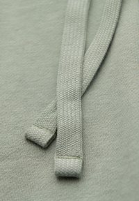 Gros plan de deux cordons tissés gris reposant sur une surface en tissu tricoté assorti.