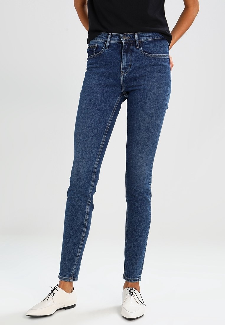 Smala blå jeans i denim med hög midja, med fem fickor och dragkedja. Matchade med vita snörskor.