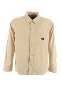 Camicia in corduroy beige con maniche lunghe, chiusura con bottoni, taschino sul petto e una piccola etichetta con logo cucita sulla tasca.