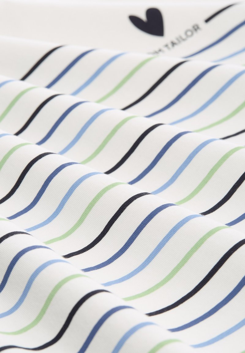 Tissu en coton avec un fond blanc mettant en avant des rayures ondulées en bleu, vert et noir. Texture lisse avec des détails de couture visibles.