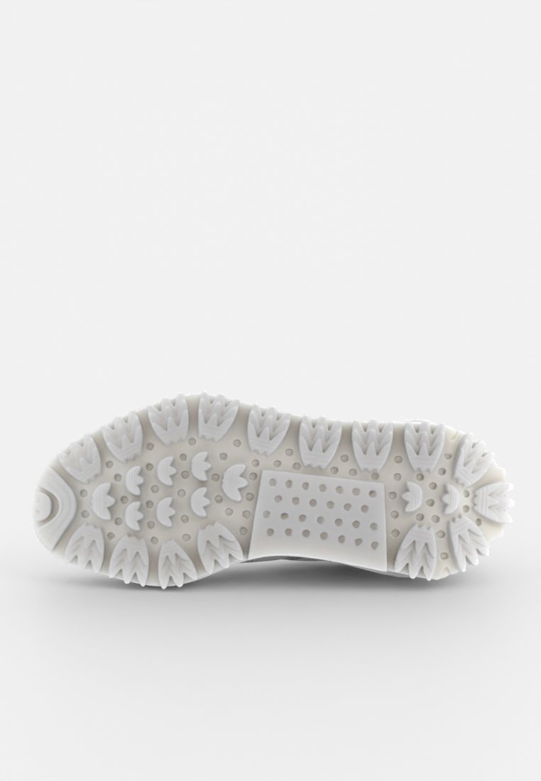 Sole di scarpa sportiva bianca con una superficie in gomma texture e a motivo, caratterizzata da impugnature circolari e triangolari per una maggiore aderenza.