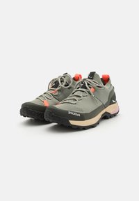 Scarpe da hiking leggere in mesh verde oliva con suola in gomma nera. Presentano accenti arancioni vivaci e una superficie texturizzata per una buona aderenza all'aperto.