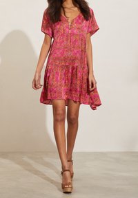 Rosa mönstrad klänning med korta ärmar, V-ringning och lagerad nederkant. Har intrikata blommönster och geometriska designer i livfulla färger.