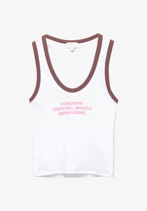 Valkoinen hihaton paita ruskealla reunuksella, jossa on pinkillä teksti: "JOSKUS VAHVA, USEIN SOPEUTUEN." Pehmeää puuvillakangasta, yksinkertainen muotoilu.