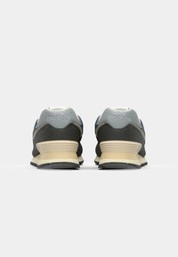 Zapatillas gris y marino con parte superior de ante y malla, que presentan una suela acolchada, un logotipo prominente y acentos texturizados en el talón.