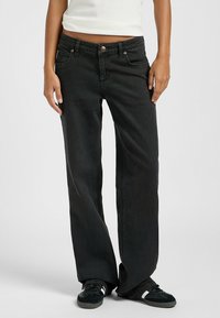 Jeans amplios negros con un diseño clásico de cinco bolsillos y un cierre de botón. La tela tiene una textura suave, con un ligero desvanecimiento en las piernas.