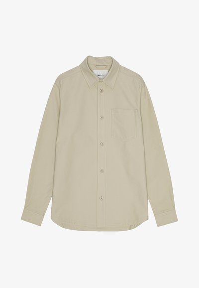 Beige långärmad skjorta med knäppning och spetsig krage, en bröstficka och subtil textur. Har kontrasterande knappar och prydlig sömnad.