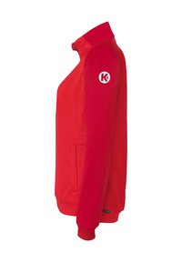 Rød zip-up jakke lavet af letvægtsstof. Har høj krave, lange ærmer, sidelommer og et logo på venstre ærme.