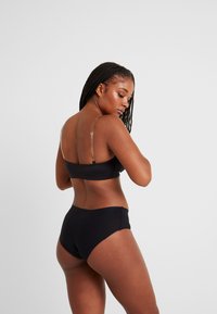 Zwart bikini set met een crop top met verstelbare doorzichtige bandjes en bijpassende hoog- taille onderkant. Glad, rekbaar materiaal met een minimalistisch ontwerp.