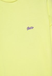 Sweat jaune avec un petit logo violet brodé sur la partie gauche de la poitrine et un col rond.