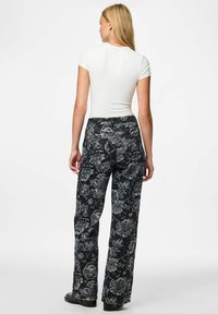 Hlače tamnoplavog uzorka s cvjetnim motivom i opuštenim krojem. Imaju pojas i vidljive džepove, izrađene od teksturirane tkanine.