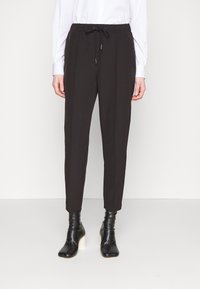 Pantalons noirs, ajustés avec une taille élastique et un cordon de serrage. Fabriqués dans un tissu lisse. Assortis avec des bottines noires ajustées.