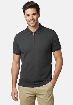 Donkergrijs poloshirt met korte mouwen en een ritskraag, met een gestructureerd patroon en een aansluitend ontwerp, gedragen met lichtbeige broeken.