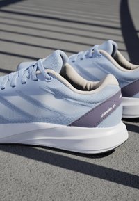 Hellblaue Sportschuhe aus Mesh und Gummi mit einem gepolsterten Kragen, weißer Sohle und einem lila Akzent mit dem Aufdruck "DURAMO RC".