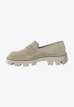 Chaussure slip-on en suede beige avec une tige texturée, une semelle épaisse à stries et deux brides superposées sur le devant. Accentuée de bordures noires.