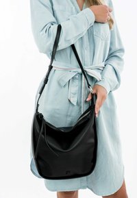 Borsa a spalla in pelle nera con chiusura a zip, texture liscia e forma curva. Dotata di tracolla staccabile e branding discreto.
