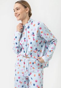 Ensemble de pyjama bleu clair avec des motifs colorés de macarons. La chemise a un col, des boutons sur le devant et une poche ; le pantalon a une ceinture élastique.