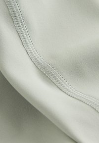 Helehall kangas siidise tekstuuriga, millel on siledad õmblused ja kerge läige. Materjal tundub kerge ja paindlik.