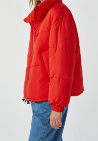 Rød polstret jakke med høj krave, lynlåslukning og elastiske manchetter; har sidelommer og et let cropped design.