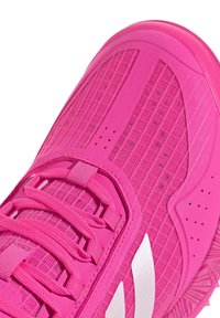 Scarpa sportiva di un vivace colore rosa, con tomaia in rete testurizzata, suola spessa, lacci e strisce diagonali bianche sui lati.