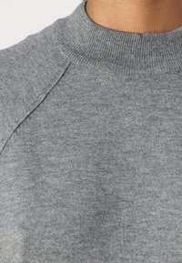 Sweater cinza com um decote redondo canelado, textura suave e detalhes de costura visíveis nos ombros. O tecido parece leve e liso.