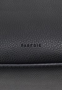 Pochette en cuir noir avec une finition texturée et le logo "PARFOIS" embossé. Design simple avec des bords nets et sans accents supplémentaires.
