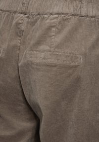 Bordeaux corduroy broeken hebben een gestructureerd oppervlak, een elastische tailleband en twee achterzakken met gestikte accenten.