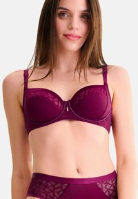 Bordeaux bh met gevormde cups, verstelbare banden en een geometrisch gaasdetail. Glad textuur met een elegante uitstraling en gouden hardwareaccenten.
