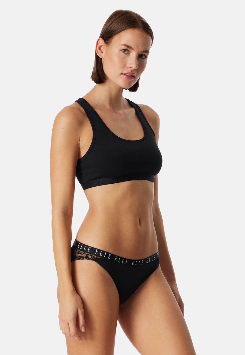 Zwarte katoenen sportbh met brede bandjes; bijpassende zwarte bikinibroekjes met een logo tailleband en kanten accenten. Overal een gladde textuur.