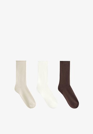Tri páry ponožiek po stred lýtok: béžové, biele a tmavo hnedé. Každý pár má hladkú textúru a jednoduchý dizajn bez vzorov alebo ozdob.