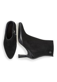 Botines de tacón alto de ante negro con un diseño elegante, que incluyen un cierre de cremallera lateral y detalles en cuero, puntera afilada y un tacón delgado.