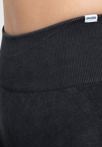 Zwarte sportlegging met een getextureerde, geribbelde tailleband. Beschikt over een gladde stofafwerking en een klein wit logo-label.