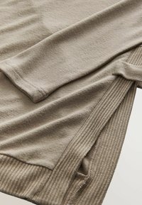 Beiger Pullover aus einem weichen, strukturierten Stoff mit einem gerippten Saum und Bündchen. Das Design enthält einen lässigen Schnitt und lange Ärmel.