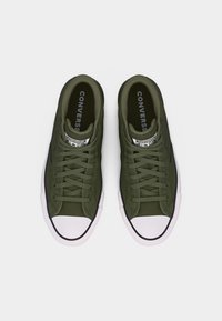 Rohelist värvi Converse madalad tossud, millel on valged kummist ninaosad ja mustad ääred, vaadatuna ülevalt valgel taustal.