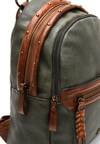 Groene leren rugzak met bruine leren riemen en koperen studs. Heeft dubbele ritsen en een geweven leren accent. Gep textured afwerking.