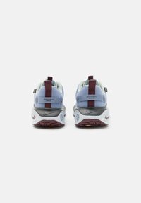 Vista posteriore di sneakers con una tomaia blu, intersuola grigia e dettagli color bordeaux. Presenta due linguette e motivi di battistrada distintivi sulla suola.