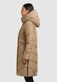 Dlouhý béžový péřový kabát s kapucí, diagonálním prošíváním, kapsou na zip na boku a logem na lemu.