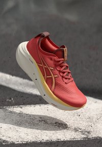 Basket rouge avec une tige texturée, accents jaunes et une semelle blanche rembourrée. Comprend un logo et un système de lacets pour un ajustement sécurisé.