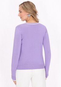 Lila Pullover mit rundem Halsausschnitt, langen Ärmeln und gerippten Bündchen. Merkmale einen weißen Saum entlang des Halsausschnitts und eine figurbetonte Silhouette.
