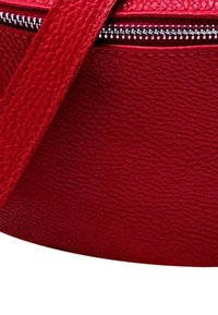 Rode gestructureerde leren handtas met een ritsluiting en een platte schouderband. Het oppervlak heeft een gebobbeld afwerking voor duurzaamheid.