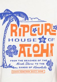 Hvid T-shirt med grafisk tekst i orange og blå: "Ripcurl House of Aloha," med illustrationer af palmetræ og hibiscusblomst.