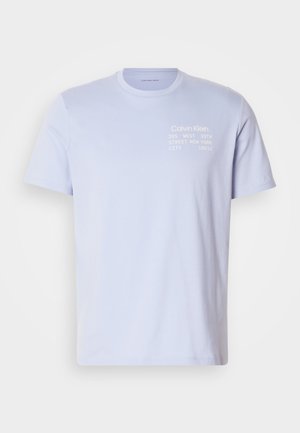 Heledsinine puuvillane T-särk ümmarguse kaelusega. Ees on valge tekst: "Calvin Klein 205 WEST 39TH STREET NEW YORK CITY 10018." Lühikesed varrukad.