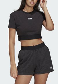 Svart kortärmad t-shirt och matchande shorts med elastisk midja och adidas-logotyp framtill. Slät yta, avslappnad passform.